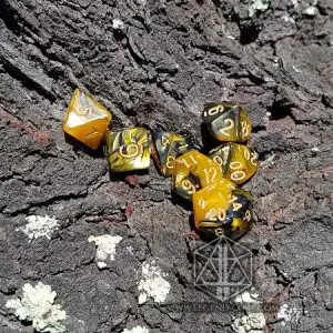 Set di sette dadi poliedrici Ashes of War, oro e nero marmorizzati con numeri dorati, su corteccia con licheni