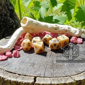 Set di dadi Bark: sette dadi poliedrici color osso antico con numeri scuri su un ceppo, tra legno secco e pietre rosse