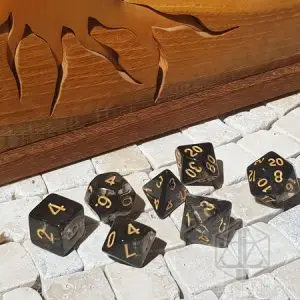 Set di dadi GdR Black Diamond: sette dadi neri fumé traslucidi con numeri dorati su piastrelle di pietra accanto a legno intagliato