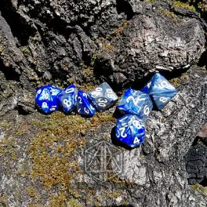 Set di sette dadi poliedrici Celestial Dragon in blu e argento marmorizzati con numeri bianchi su corteccia con muschio