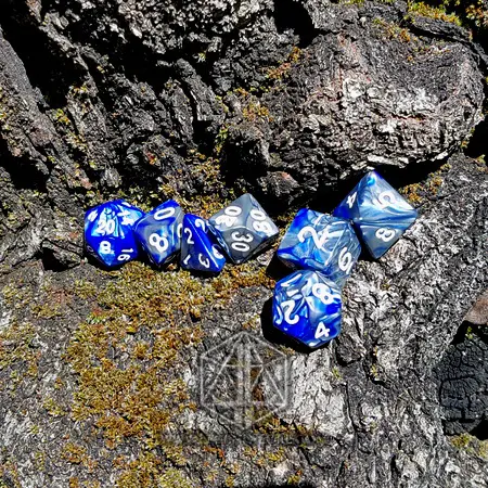 Celestial Dragon set of seven polyhedral dice in swirled blue and silver with white numbers, resting on mossy tree bark