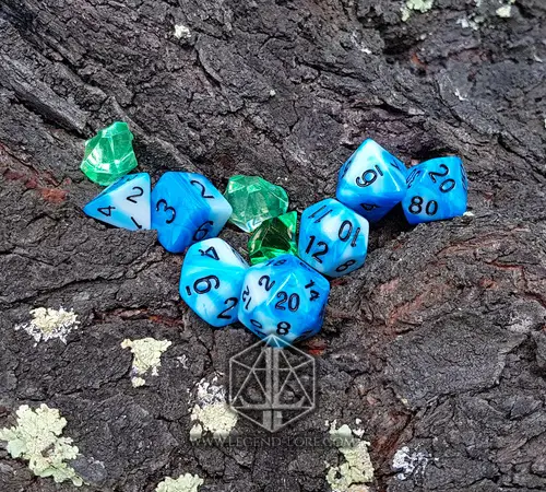 Cloud RPG dice set: seven blue and white swirled polyhedral dice with black numbers on tree bark, beside green crystals
