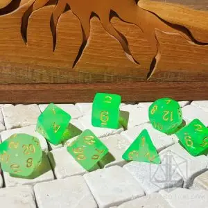 Set di dadi GDR Cloudy Emerald: sette dadi poliedrici verde brillante traslucidi con numeri dorati su piastrelle di pietra