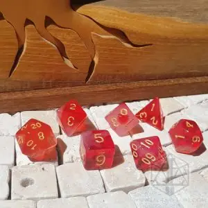 Set di sette dadi poliedrici Cloudy Ruby rosso traslucido con numeri dorati su piastrelle di pietra bianca e legno intagliato
