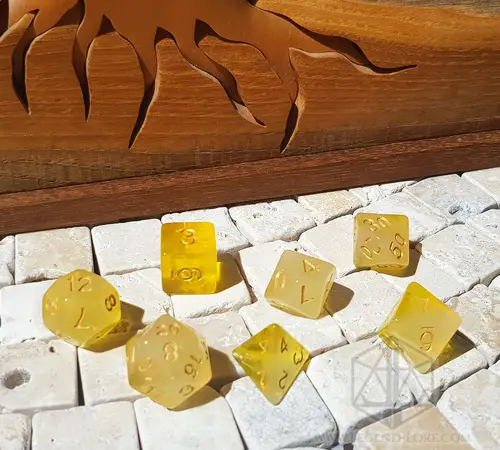 Topazio Impuro 1 Set di dadi GDR Cloudy Topaz: sette dadi poliedrici giallo traslucido velato con numeri dorati su piastrelle di pietra
