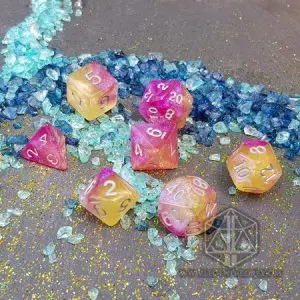 Set di dadi GdR Crazy Dream: sette dadi galaxy rosa e gialli con glitter e numeri bianchi su frammenti di vetro azzurri