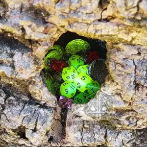 Dadi poliedrici Night Jade verdi fosforescenti nella cavità di una corteccia con monete verdi e gemme rosse e viola