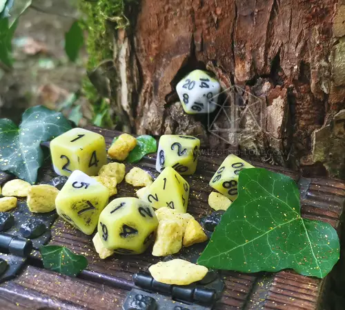 Pale Death RPG dice set, seven pale yellow and white antique-style dice with black numbers among stones, ivy and tree bark