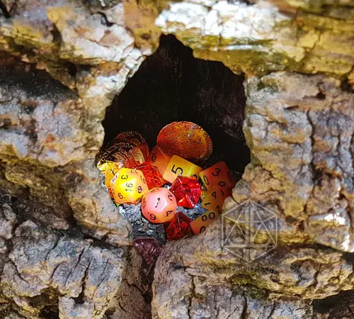 Persistent Twilight RPG dice set in translucent orange, yellow and red, piled in a hollow of weathered tree bark