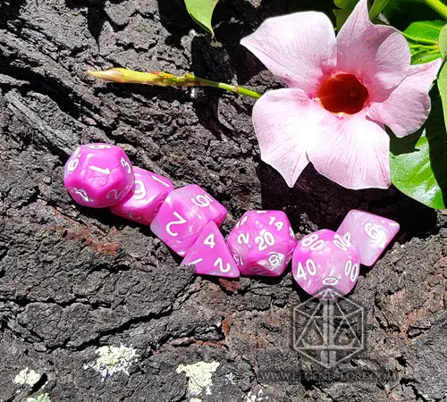 Roses and Flowers RPG dice set: seven swirled pink and white polyhedral dice on tree bark beside a pink flower