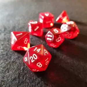 Set di dadi GDR Ruby: sette dadi poliedrici rossi trasparenti con numeri bianchi su feltro grigio scuro, D20 in primo piano