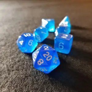 Set di dadi GDR Sapphire: sette dadi poliedrici blu traslucidi con numeri bianchi su un panno scuro
