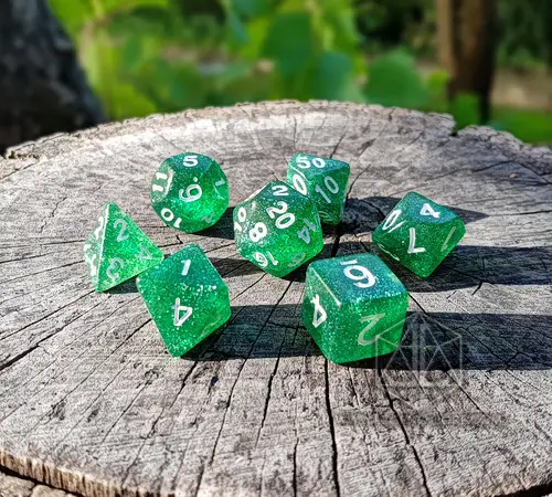 Foresta Brillante 2 Set di dadi GdR Shining Forest: sette dadi poliedrici verdi trasparenti glitterati con numeri bianchi su un ceppo