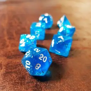 Set di sette dadi GdR Shining Sea in resina blu trasparente glitterata con numeri bianchi su una superficie in pelle marrone