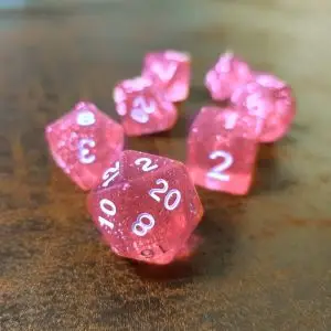 Set Sparkling Fire di sette dadi poliedrici rosa trasparenti con glitter e numeri bianchi su una superficie in legno