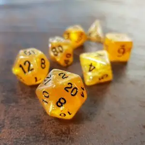 Set di dadi GdR Sparkling Gold: sette dadi poliedrici oro trasparenti con glitter e numeri neri su un tavolo di legno scuro