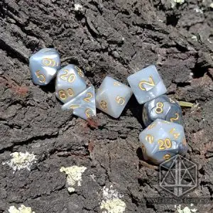 Set di dadi GdR Steel Dragon: sette dadi poliedrici grigi e bianchi marmorizzati con numeri dorati su corteccia