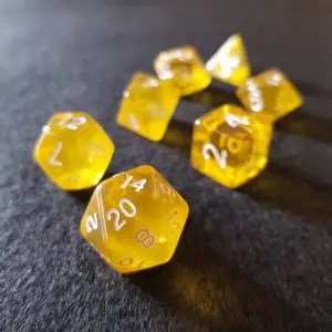Set di dadi GdR Topaz: sette dadi poliedrici gialli trasparenti con numeri bianchi su feltro grigio scuro