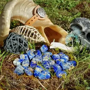 Rune divinatorie Night Shards in lapislazzuli con simboli dorati sul muschio, accanto a corno di ariete e teschio grigio