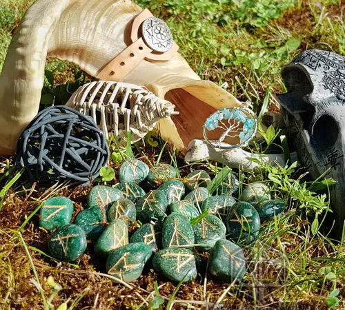 Rune divinatorie Seer Eyes in avventurina verde con simboli dorati sul muschio, tra corno, scheletro, ciondolo e teschio