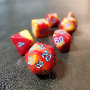 Set Celestial Flammes di sette dadi poliedrici rossi e gialli marmorizzati con numeri blu su superficie in pelle scura