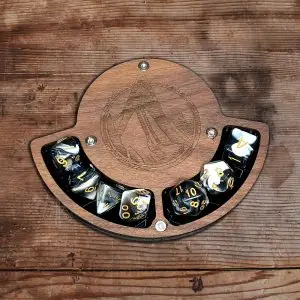 Stone Platform RPG dice coaster in wood with engraved mountain, holding seven black and white swirl dice with gold numbers