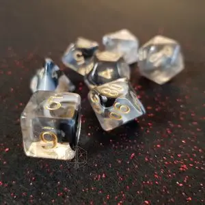 Set di dadi GdR Wright: sette dadi poliedrici in resina trasparente e nera con numeri dorati su tessuto glitterato rosso