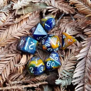 Set di sette dadi GdR Marine Bark blu e ambra con glitter stardust e numeri bianchi, su aghi secchi di sequoia