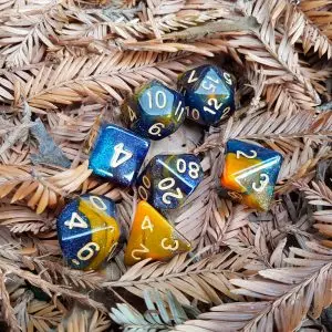 Set di sette dadi poliedrici Yggdrasil blu e arancio ambra glitterati con numeri dorati, su aghi di pino secchi