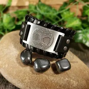 Gift of the Black Tree Viking bracelet in black braided leather with silver Celtic tree of life plate, on a stone with hematite