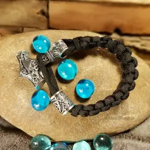 Mjolnir Viking Paracord Bracelet in black braided cord with silver Thor's hammer and Celtic beads on a stone with blue glass