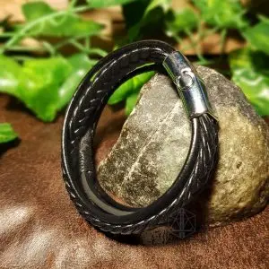 Night Pathfinder Viking bracelet with black braided and smooth leather bands and silver clasp, resting on a stone