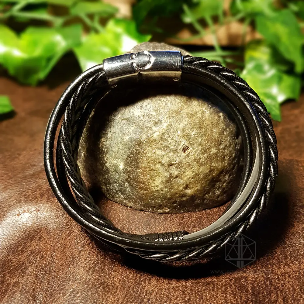 Night Pathfinder - Viking Leather Bracelet 3 Night Pathfinder Viking bracelet with braided and smooth black leather strands and silver clasp, wrapped around a stone
