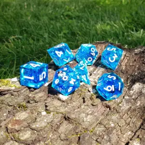 Set Glimmerwater Reliquary di sette dadi in resina blu trasparente a spigoli vivi, con glitter e numeri bianchi su un tronco