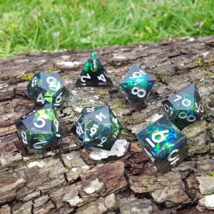 Set di dadi in resina a spigoli vivi Wyrdwood Emberglass: sette dadi fumé con foil verde-blu e numeri bianchi su corteccia