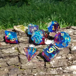 Set di sette dadi in resina a spigolo vivo Stormtide Prismstones, blu e rossi con numeri dorati e scaglie iridescenti su corteccia