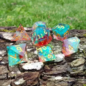 Set di dadi in resina Dawnflare Crystals a spigoli vivi, sette dadi iridescenti verde acqua e rossi con numeri dorati su corteccia