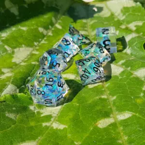 Set di sette dadi in resina a spigoli vivi Froststar Shards, trasparenti con foglia blu iridescente e numeri neri su una foglia