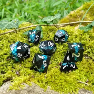 Set di dadi in resina Obsidian Shards: Crystal Weave, neri a spigolo vivo con scaglie turchesi e numeri argento sul muschio
