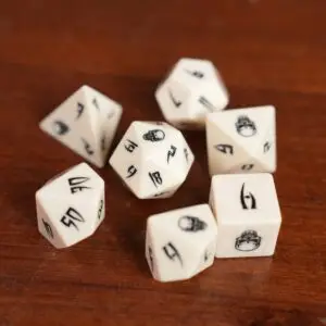 Set di dadi in osso Ivory Reliquary: sette dadi poliedrici avorio con numeri runici neri e teschi su un tavolo di legno