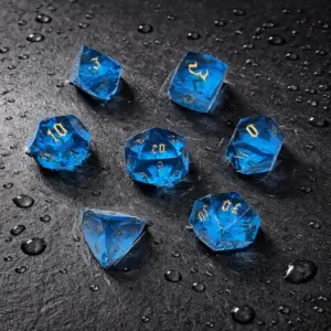 Set Aethercut di sette dadi in resina taglio diamante, blu trasparente con numeri dorati su ardesia nera bagnata
