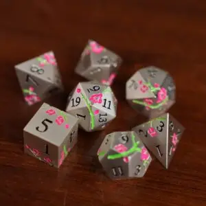 Set di dadi in metallo Silver Sakura: sette dadi poliedrici argento opaco con fiori di ciliegio rosa e rami verdi su legno