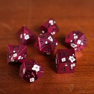 Set di dadi in metallo Crimson Sakura: sette dadi poliedrici rossi con fiori di ciliegio bianchi e numeri neri su legno