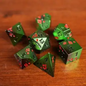 Set Verdant Sakura di sette dadi poliedrici in metallo verde con fiori di ciliegio rossi e numeri neri su un tavolo di legno