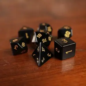 Set di dadi in pietra Voidglass: sette dadi poliedrici neri lucidi con numeri gotici dorati su un tavolo di legno