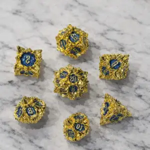 Set di dadi in metallo Azure Rose: sette dadi poliedrici dorati con bordi a petali appuntiti e numeri smaltati blu su marmo