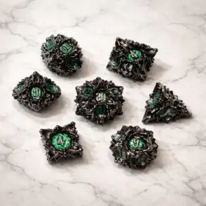 Set di dadi in metallo Eldritch Rose: sette dadi poliedrici neri a forma di rosa spinosa con facce smaltate verdi su marmo