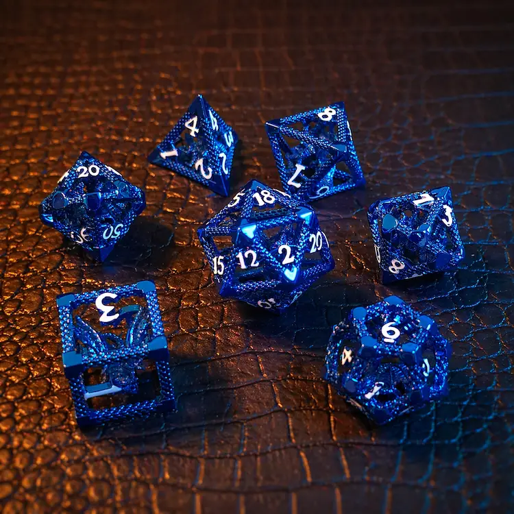 Cobalt Drake hollow metal dice set: seven glossy blue polyhedral dice with white numbers and dragon details on textured leather