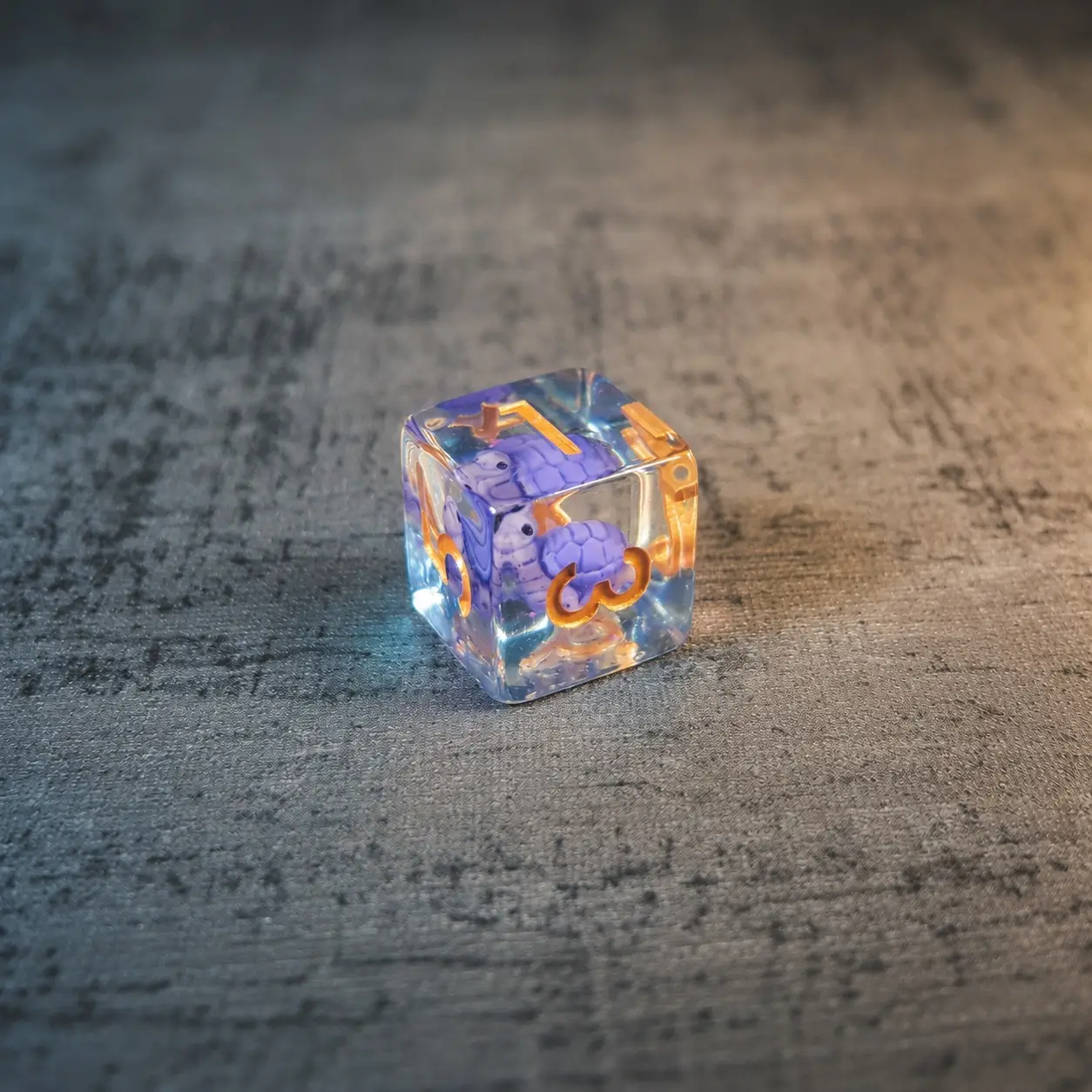 Lilac Shellback – Set di Dadi in Resina con Miniature 4 D6 Lilac Shellback in resina trasparente con piccole tartarughe viola all'interno e numeri dorati su superficie grigia