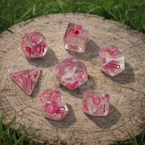 Set di dadi in resina Fairycap Miniatures: sette dadi trasparenti con inclusioni rosa e numeri rossi su un ceppo